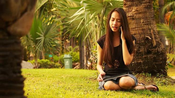 亚洲女子打电话和在平板电脑上冲浪