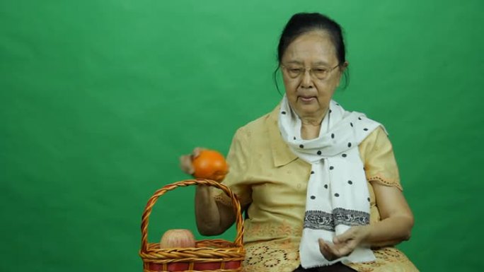 老妇人展示果篮里的橙子
