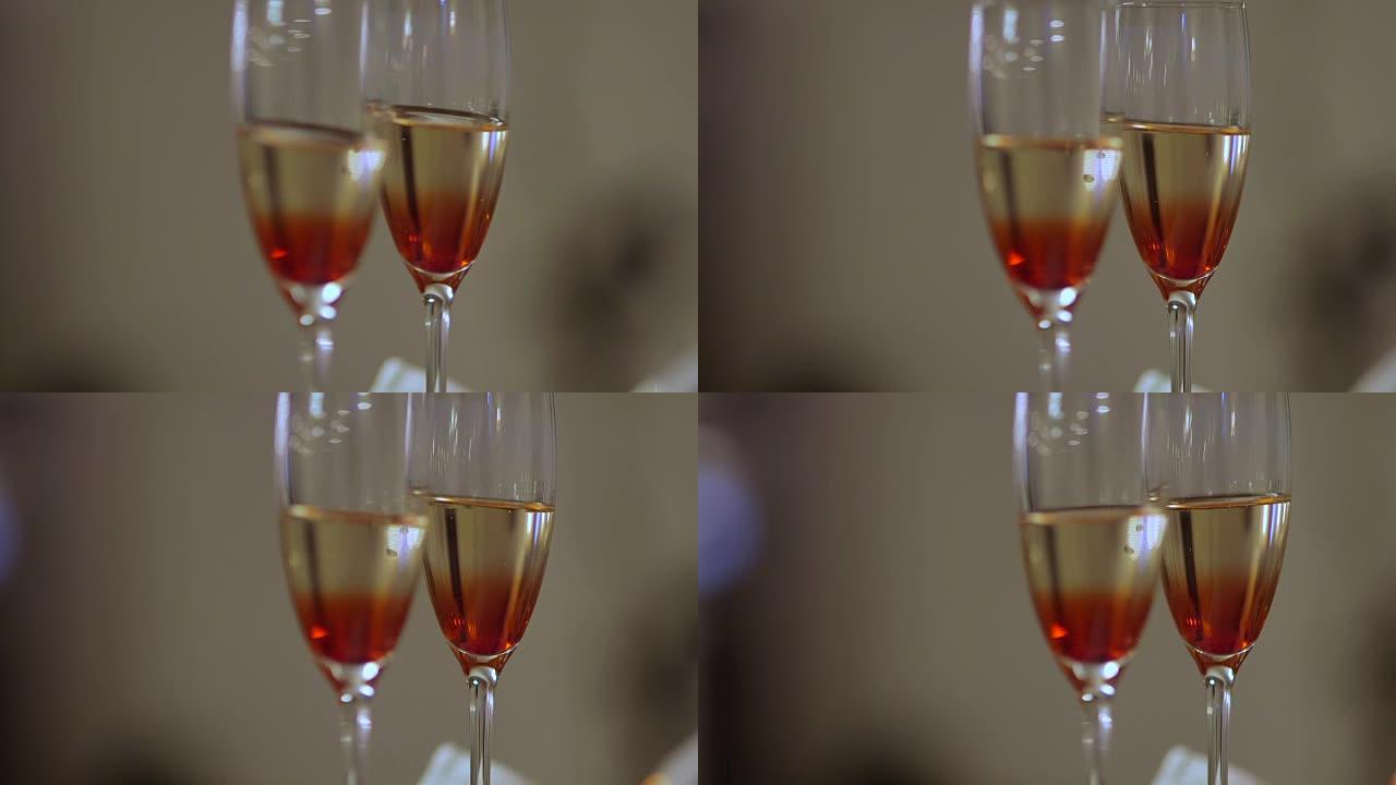 桌子上装饰着花的香槟酒杯的画面。在婚礼庆典上用手摇酒杯。