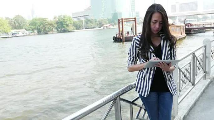 女人在河边的平板电脑上使用