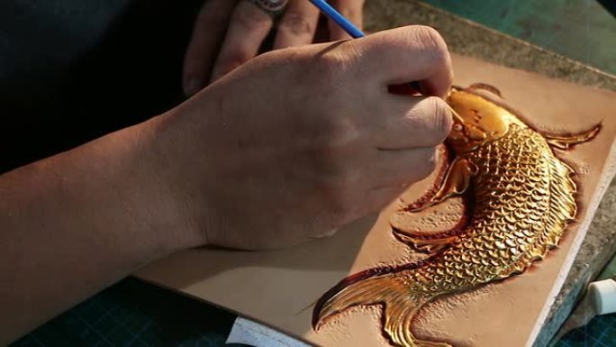 皮革工人在皮革上绘制鱼图案
