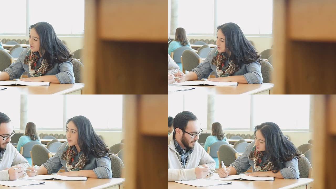 西班牙裔成年男女学生在大学图书馆同桌学习