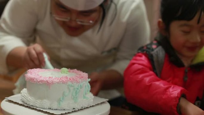 当女婴吃糖果时，厨师在生日蛋糕上撒上奶油