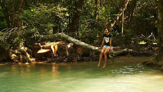 女人坐在河边的树枝上