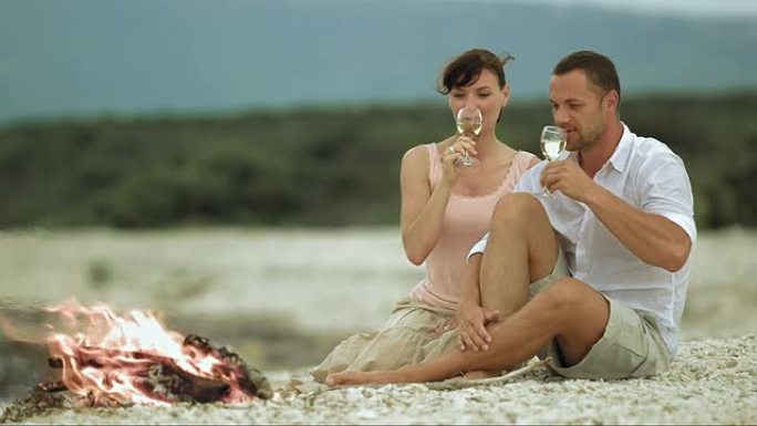 SLO MO夫妇在海滩上用火敬酒