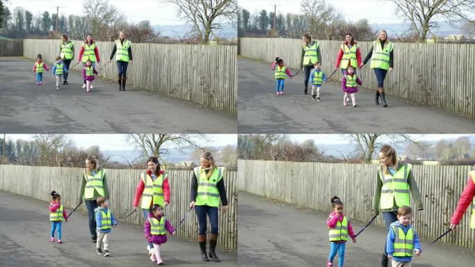 幼儿园小组与戴安全带的儿童一起散步