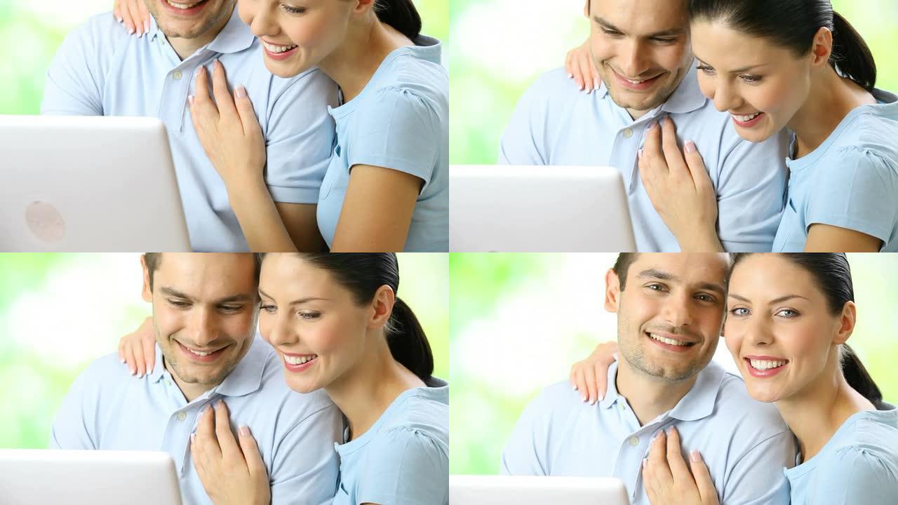 情侣在户外拿着笔记本电脑，微笑着，拥抱着，看着相机