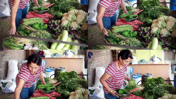 亚洲裔印度老年妇女在蔬菜水果店买蔬菜