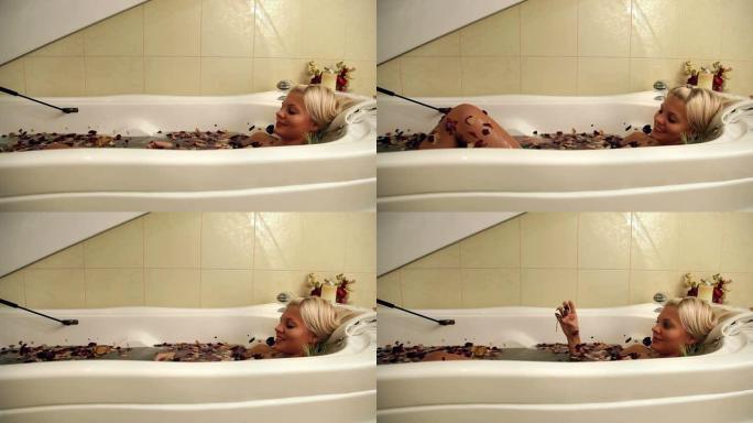 美丽的女人在热水浴缸与花瓣