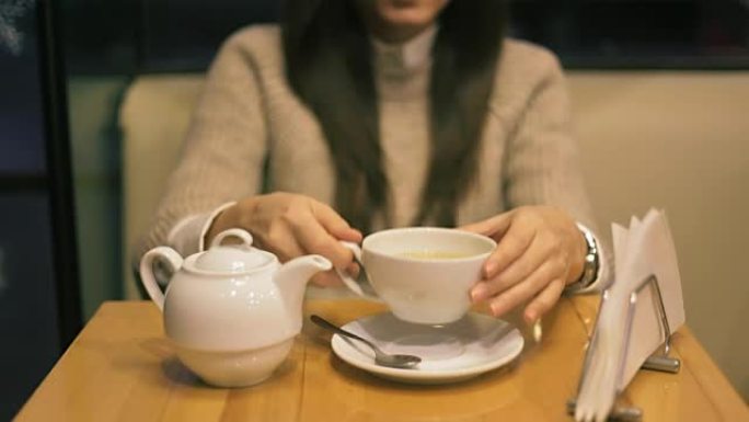 年轻女子在茶馆里喝热茶。