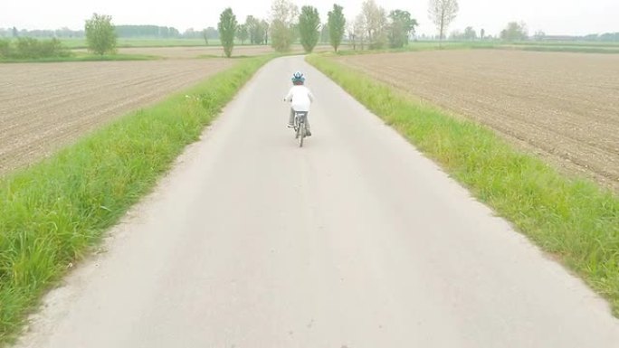 一个小男孩骑着自行车在乡间小路上
