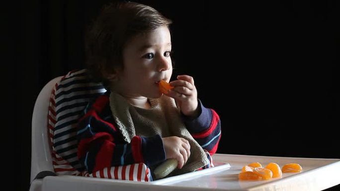 男婴坐在高脚椅上吃水果