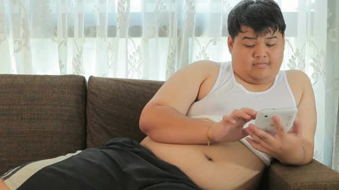 亚洲人一个男人用平板电脑在沙发上放松