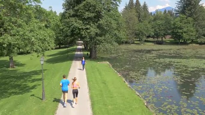 一男一女在公园里沿着湖边奔跑的天线