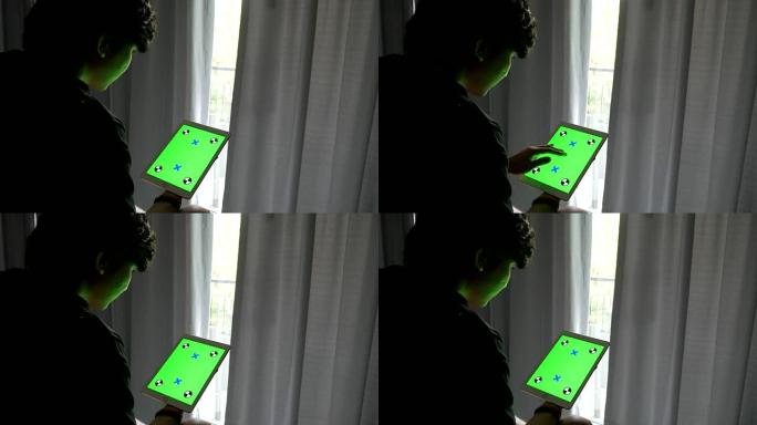 男人坐在床上，使用带有绿色屏幕的平板电脑