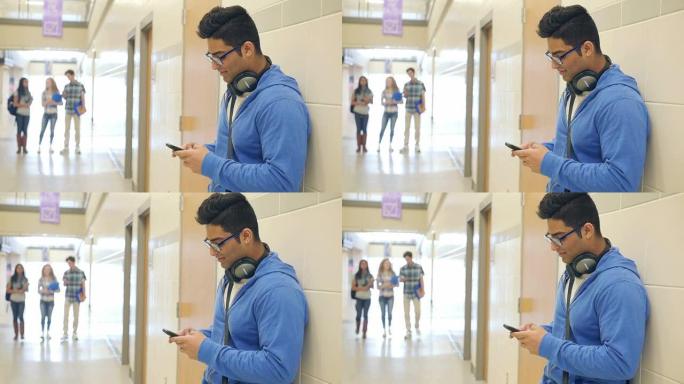 印度高中男生站在走廊用智能手机发短信
