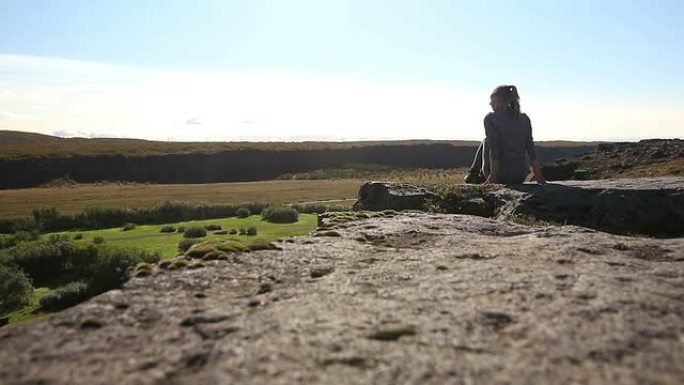 坐在冰岛悬崖边缘的年轻女子