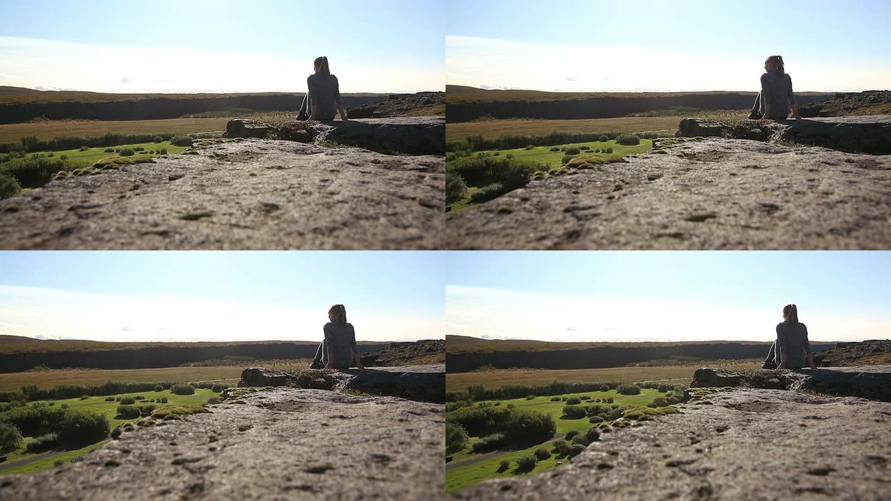 坐在冰岛悬崖边缘的年轻女子