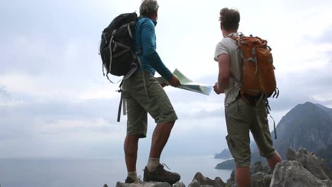 徒步旅行者在海面和山脉上方的山脊上看地图