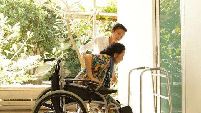年轻的看护人帮助坐在轮椅上的老年妇女