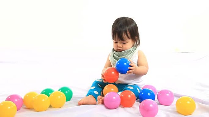 婴儿在白色背景上玩彩色球
