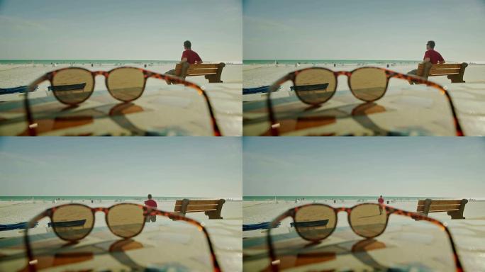 海滩上前景中的太阳镜背景中的人物