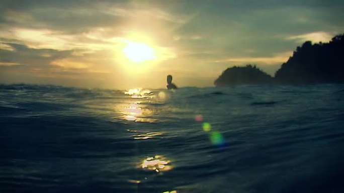 水中冲浪者观看日落