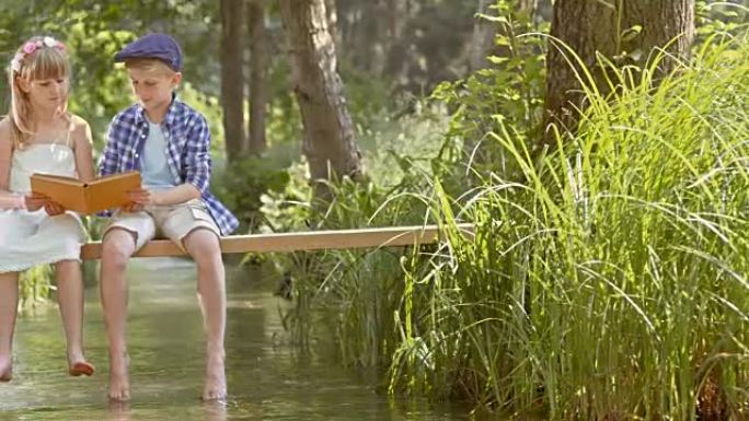 SLO MO男孩和女孩坐在人行天桥上阅读
