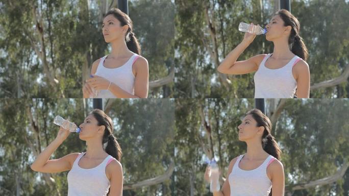 年轻女子运动后喝水。