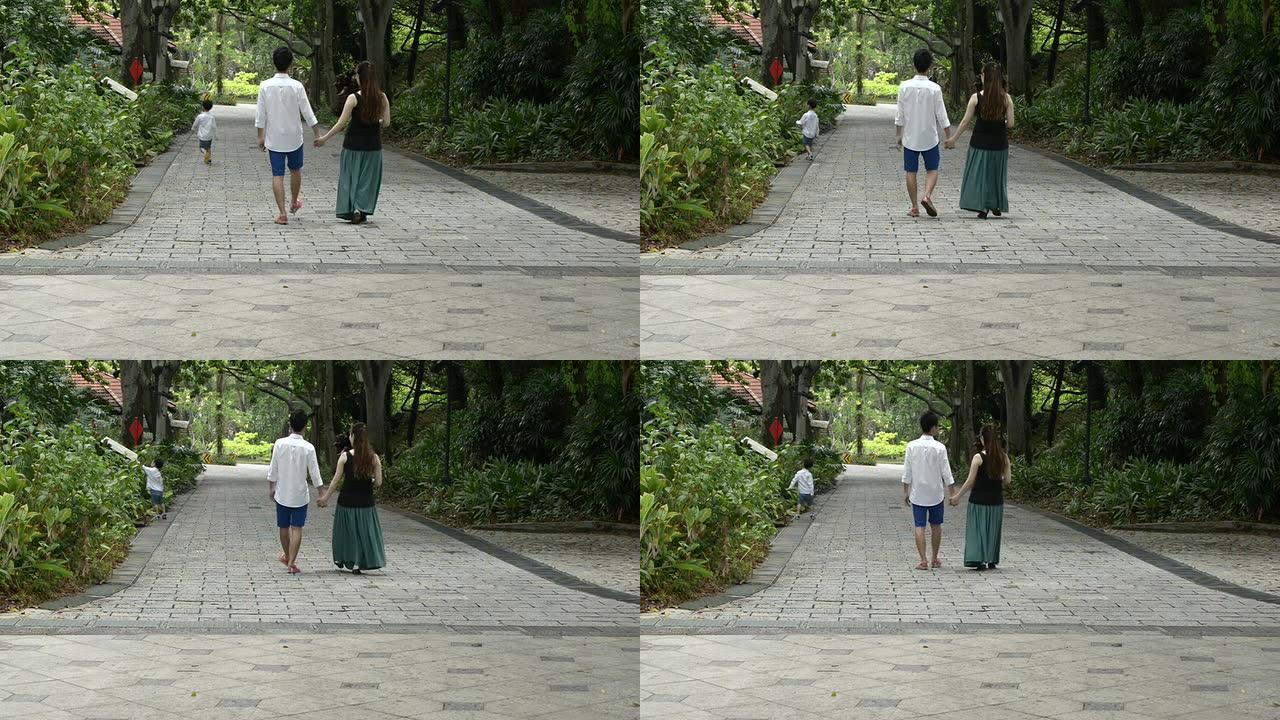 年轻的亚洲华人家庭在公园里漫步