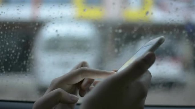 在雨天使用智能手机的车窗后面的妇女。
