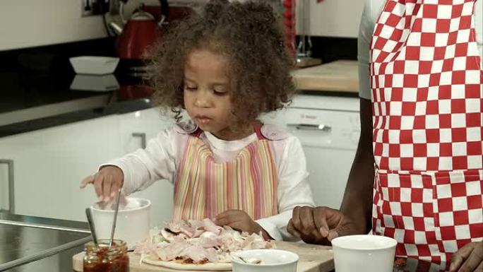 高清: 小混血儿女孩在照顾者/母亲的监督下吃披萨配料