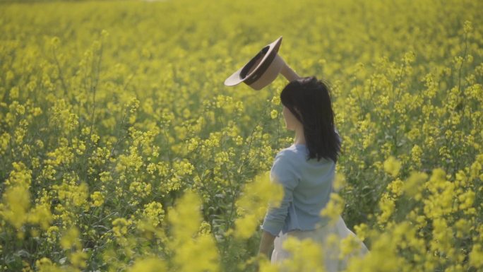 女生油菜花地挥手挥舞草帽向往自由春天踏青