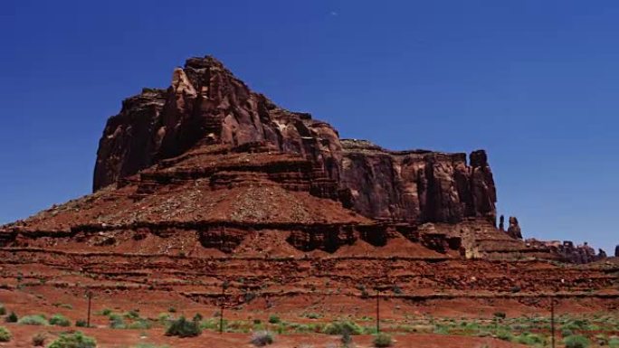 沙漠中美丽的巨大红色岩层。与湛蓝的夏日天空和明亮的绿色灌木形成对比。最初在6K的红龙上拍摄。