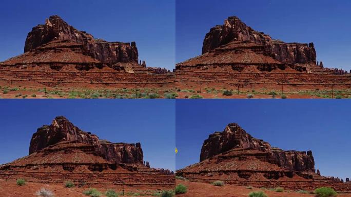 沙漠中美丽的巨大红色岩层。与湛蓝的夏日天空和明亮的绿色灌木形成对比。最初在6K的红龙上拍摄。