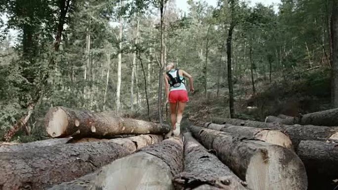 SLO MO DS女人在森林里跑过原木堆