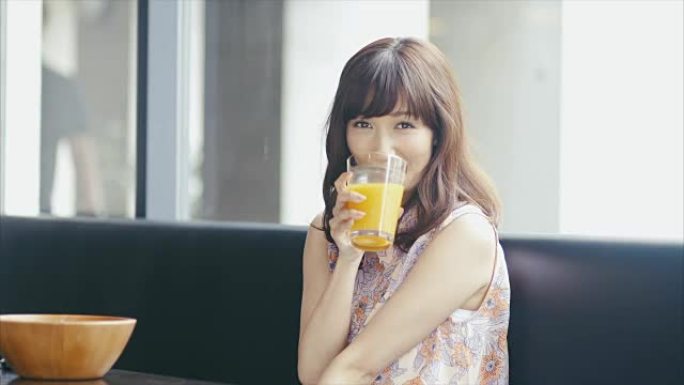 可爱的亚洲女孩在餐厅喝一杯果汁