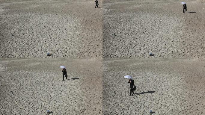 孤独的商人打着伞在沙漠中行走