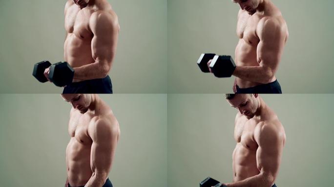 美丽的运动员在灰色背景下训练哑铃