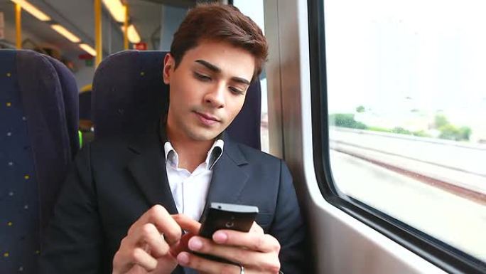 高清：年轻的商人在火车上使用手机。