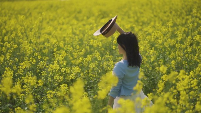 女生油菜花地挥手挥舞草帽向往自由春天踏青