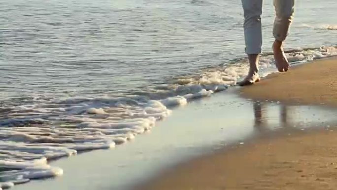 日落时男子踩在沙滩上的特写