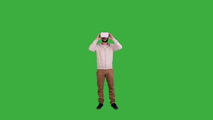 男人戴着眼镜虚拟现实并在绿色背景上享受