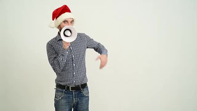 年轻的成年胡须男子在灰色背景上戴着帽子的扩音器展示复制空间圣诞老人