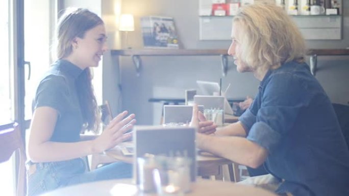 年轻女子在咖啡店与朋友聊天