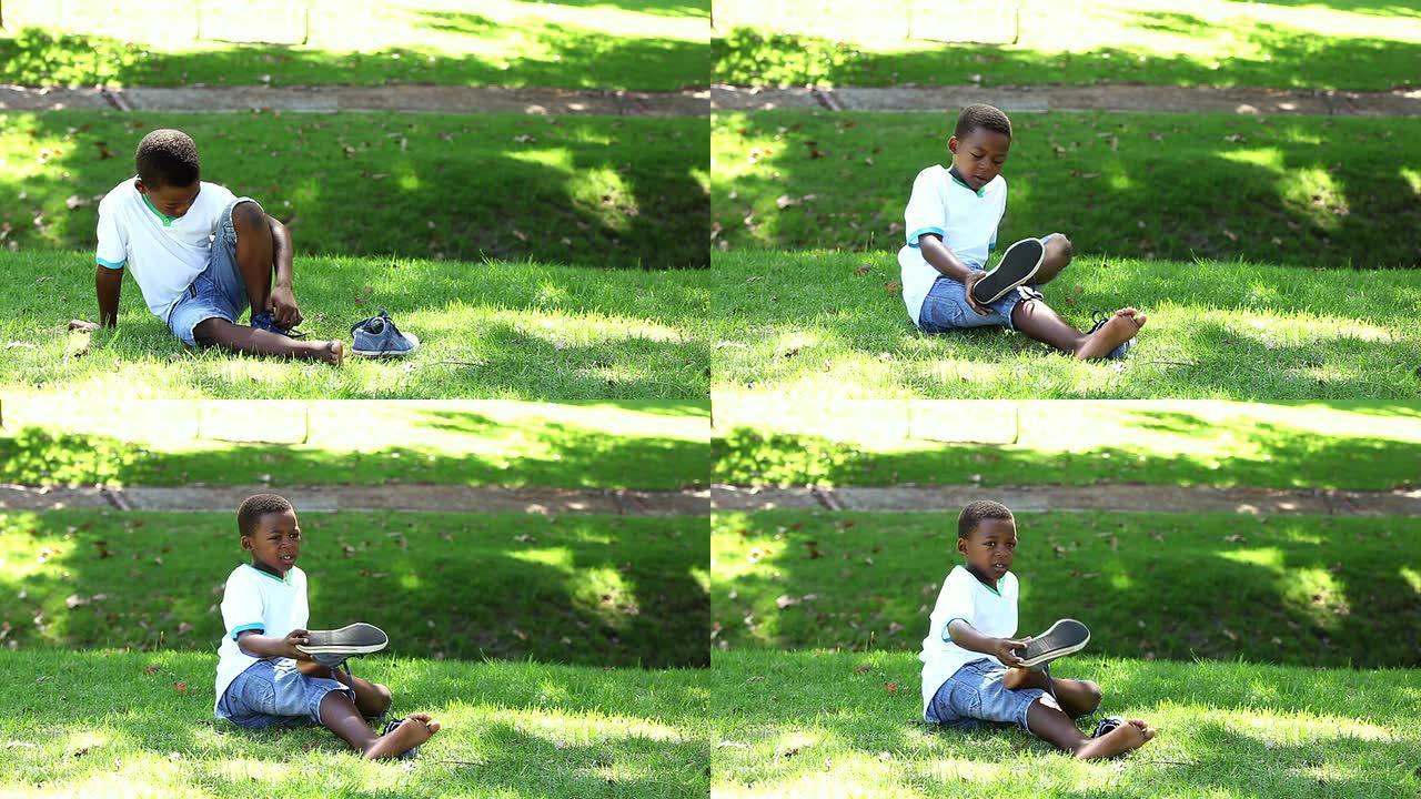 小男孩坐在草地上脱下鞋子