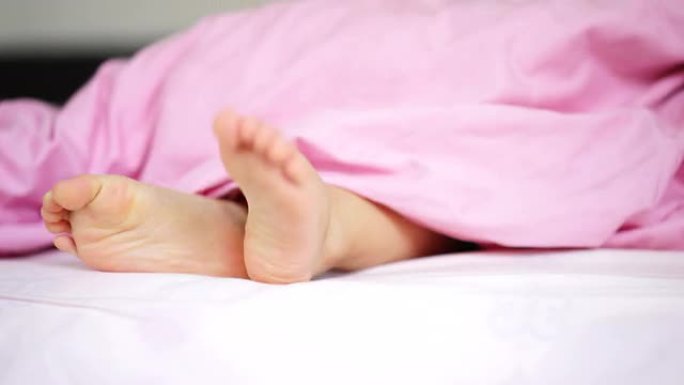 一名亚洲幼童在床上展示双脚