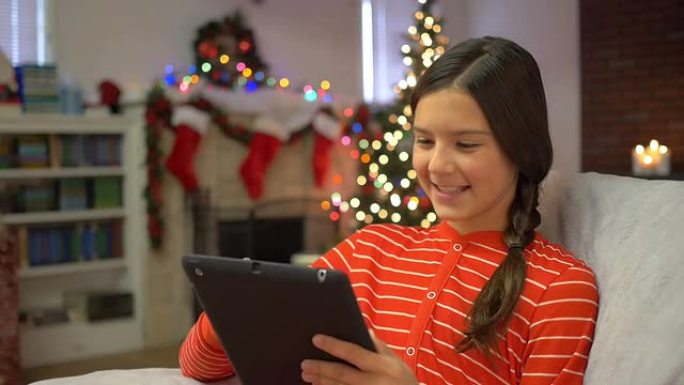 Preteen女孩在圣诞节使用新的数字平板电脑
