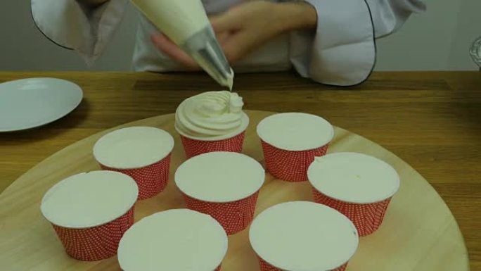 厨师在纸杯蛋糕上的滚边奶油特写