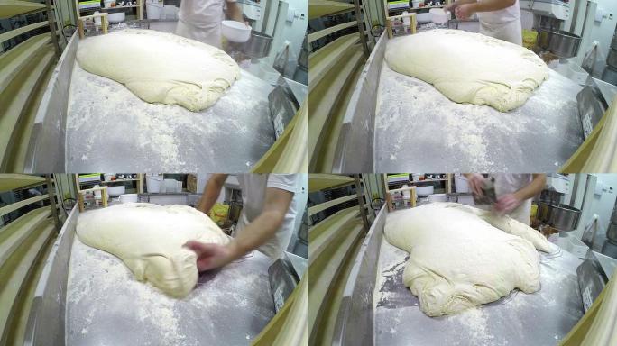 面包师在工作台上的发酵面团上撒面粉